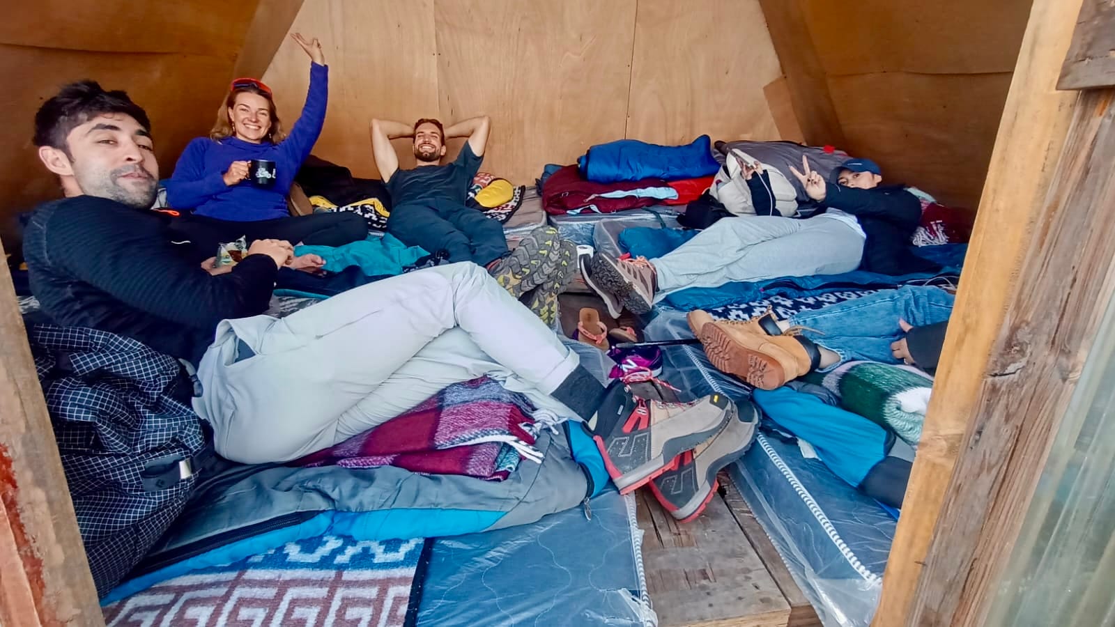 Travelers resting inside an A-frame cabin at base camp