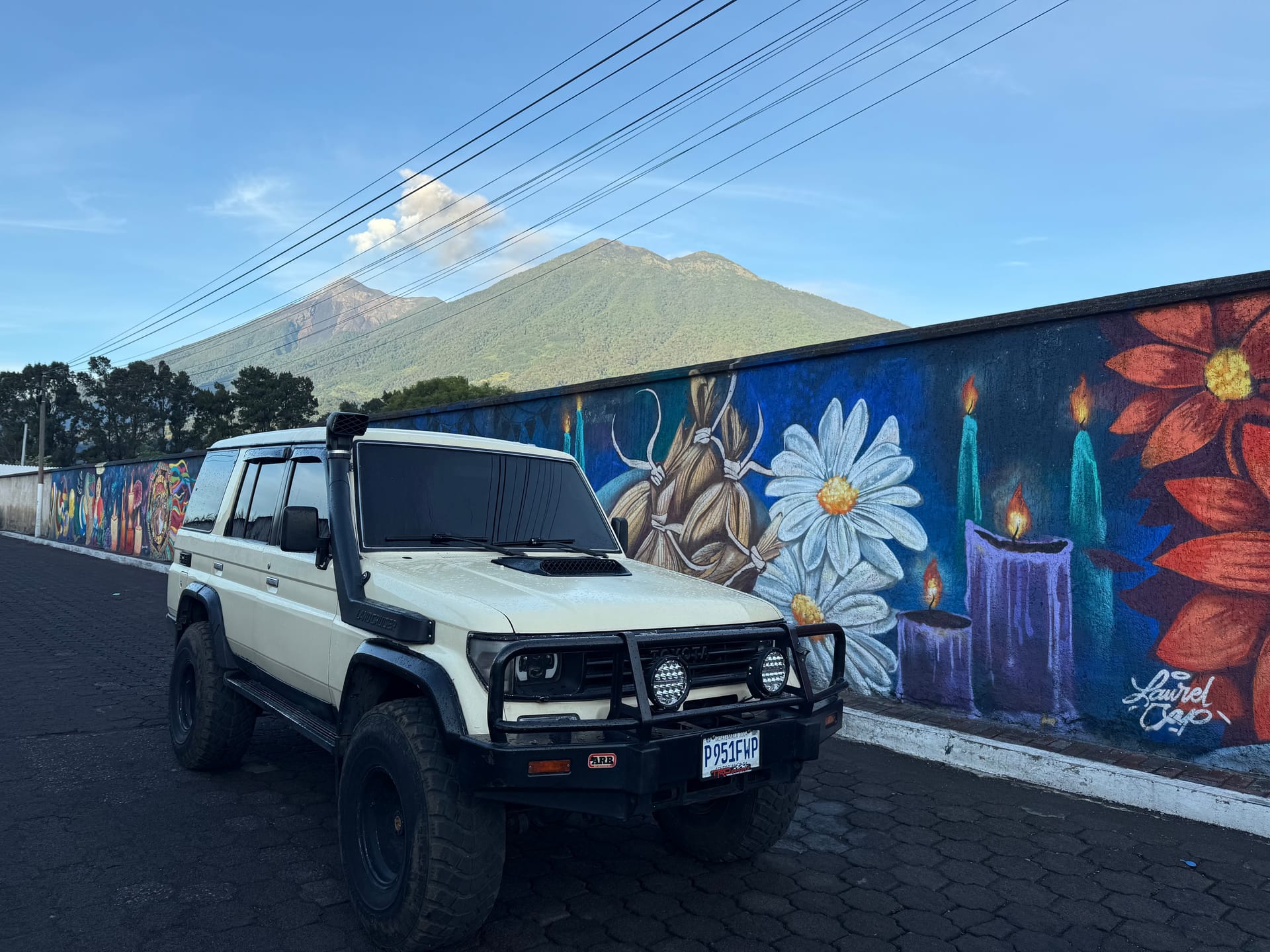 Toyota Land Cruiser 4x4 by a colorful mural below the volcanoes
