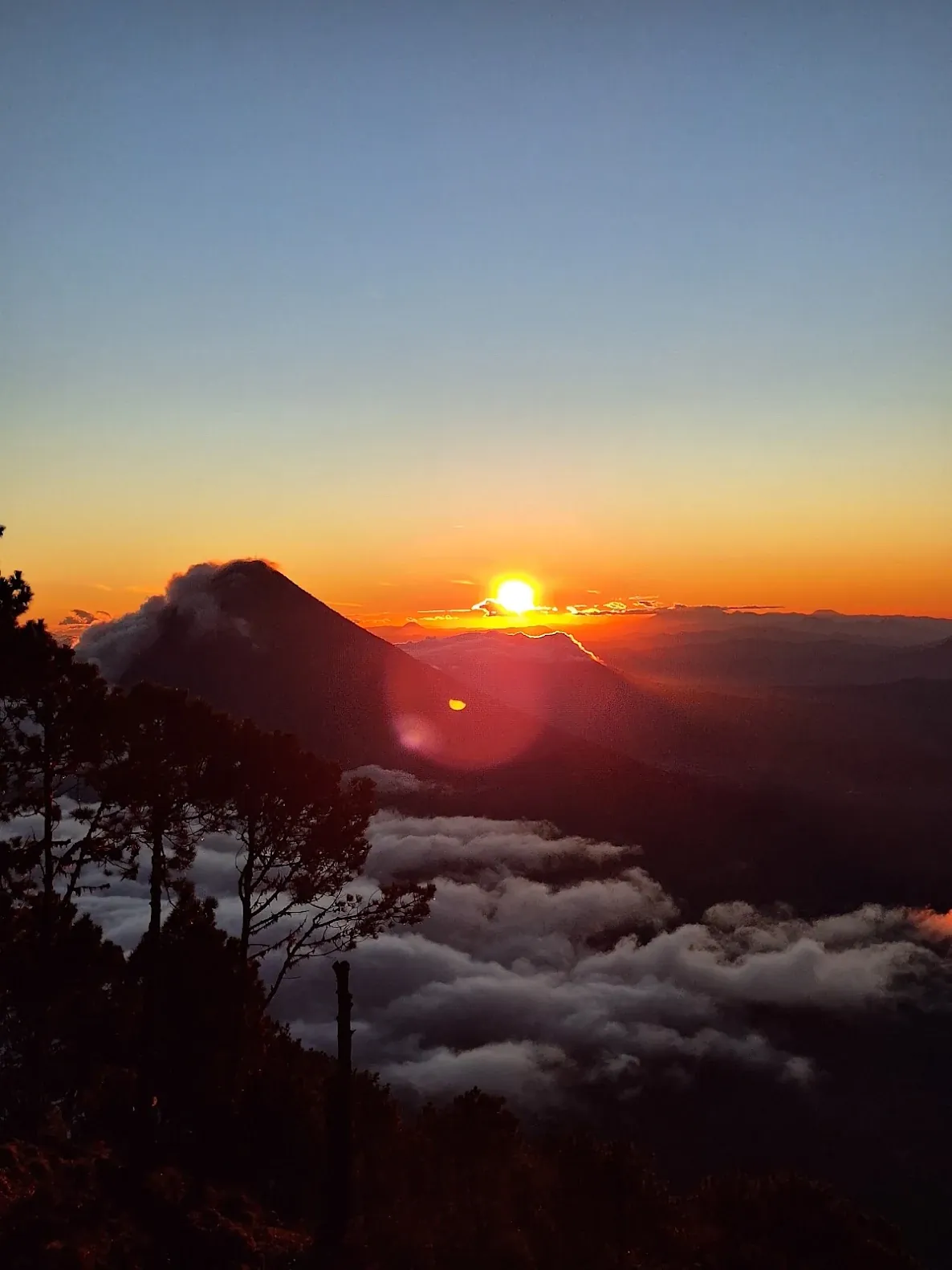 Sun rising behind Agua Volcano over a sea of clouds, seen from Acatenango