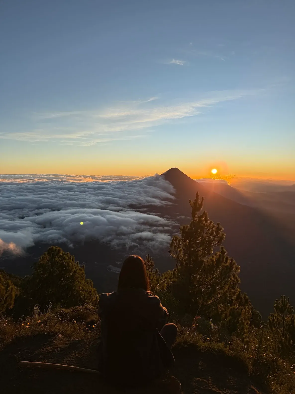 Hiker watching the sunrise above the clouds from the Acatenango summit on the 4x4 sunrise tour