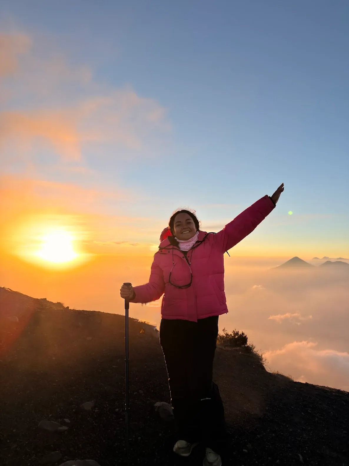 Hiker at the Acatenango summit at sunrise above a sea of clouds