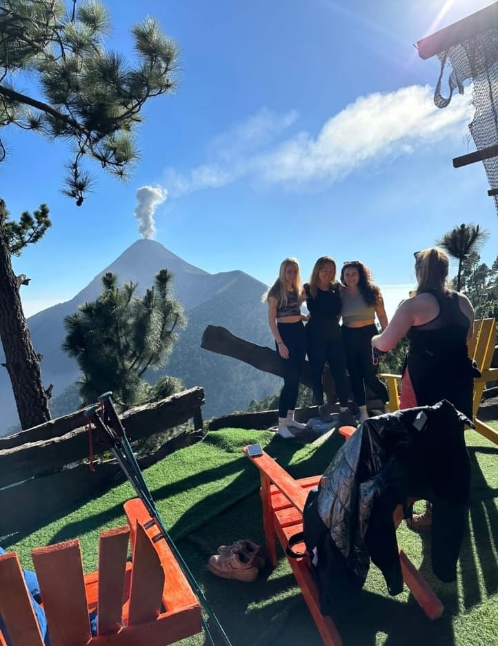 Travelers at the base camp with Volcán de Fuego smoking behind them